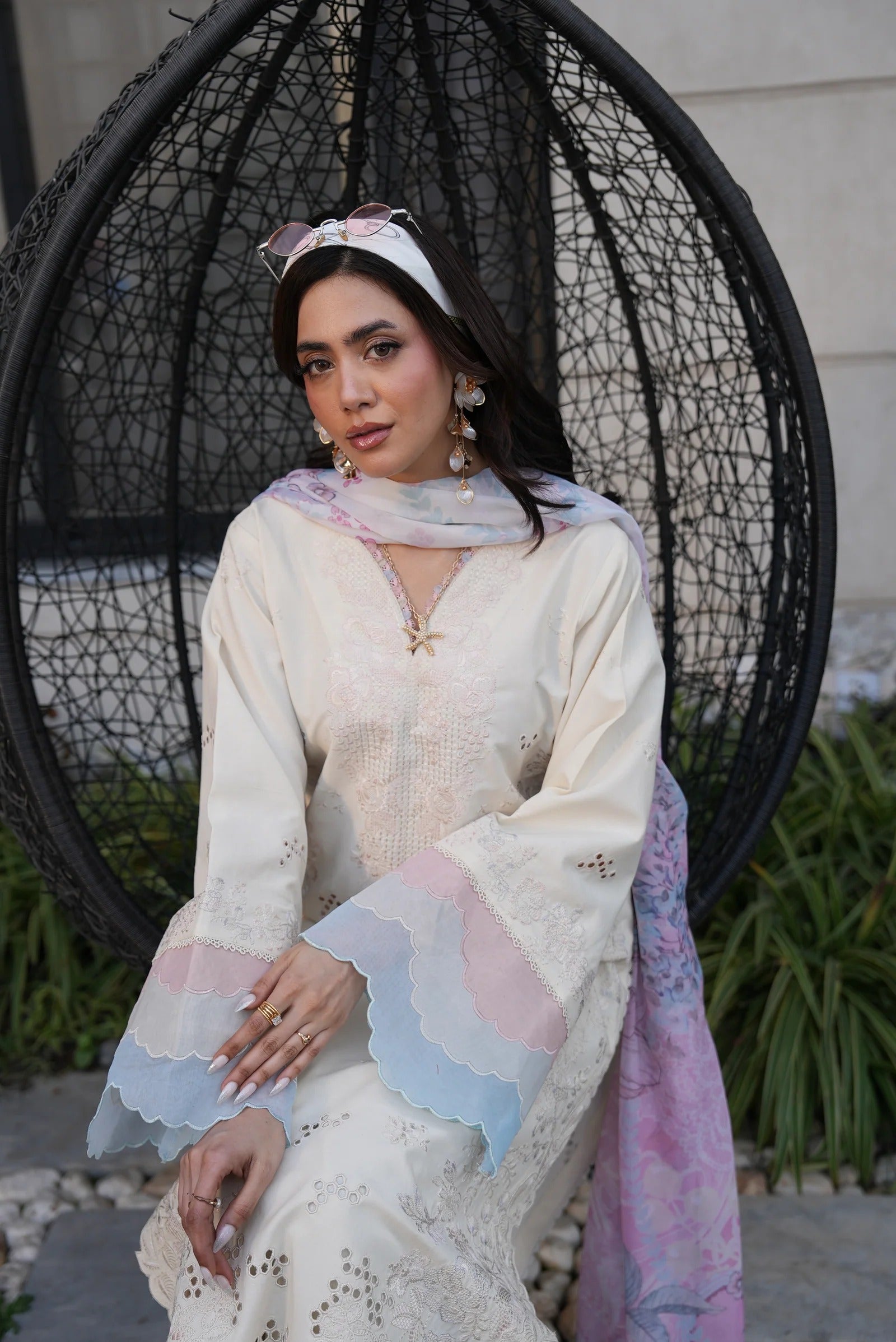 Woman in a white traditional outfit with a colorful scarf sitting in a decorative chair.
