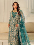 Woman in a teal embroidered traditional outfit with a sheer dupatta in a room.