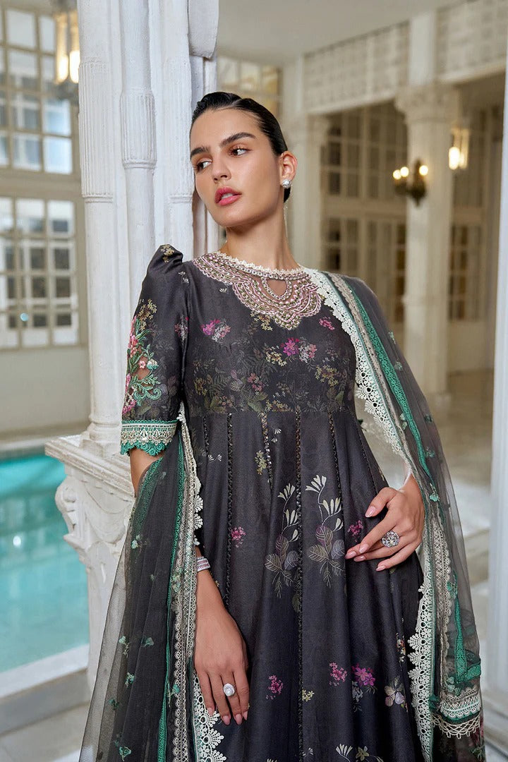 Woman in an embroidered dark gray traditional outfit standing in a decorative interior setting.