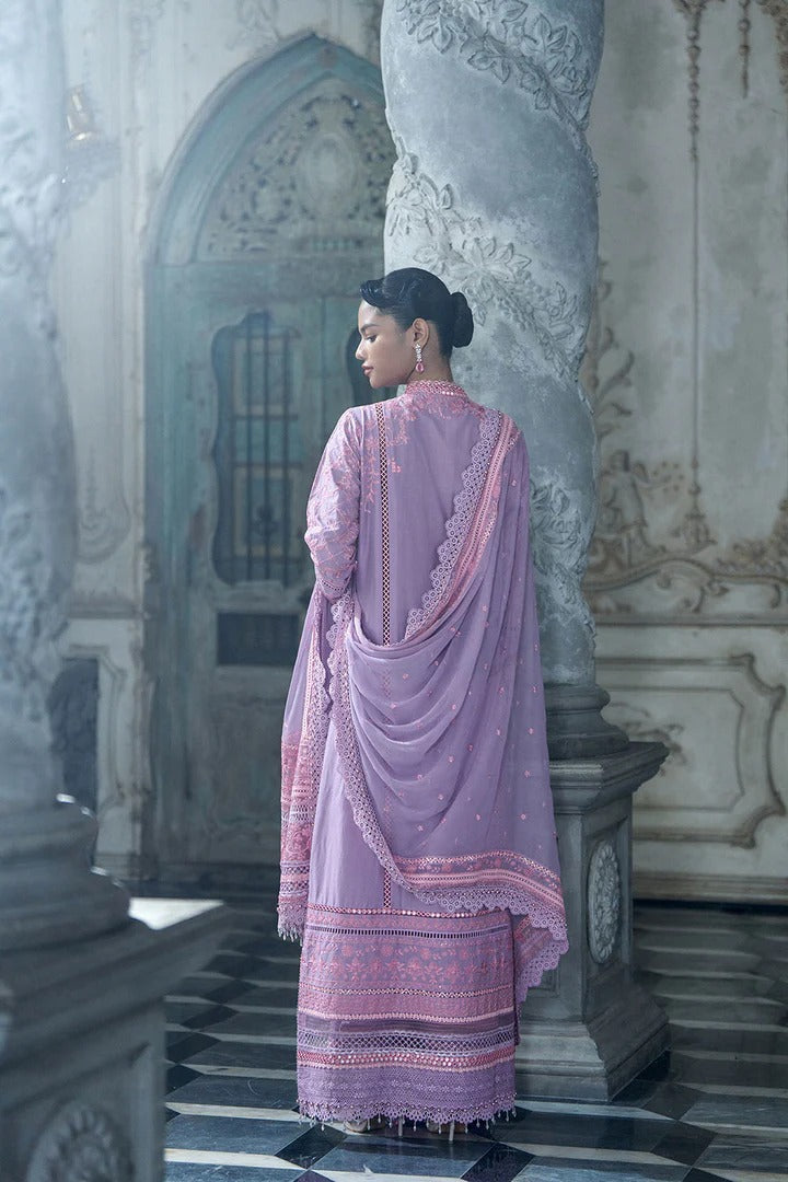 Woman in a lavender traditional outfit standing in an ornate architectural setting.