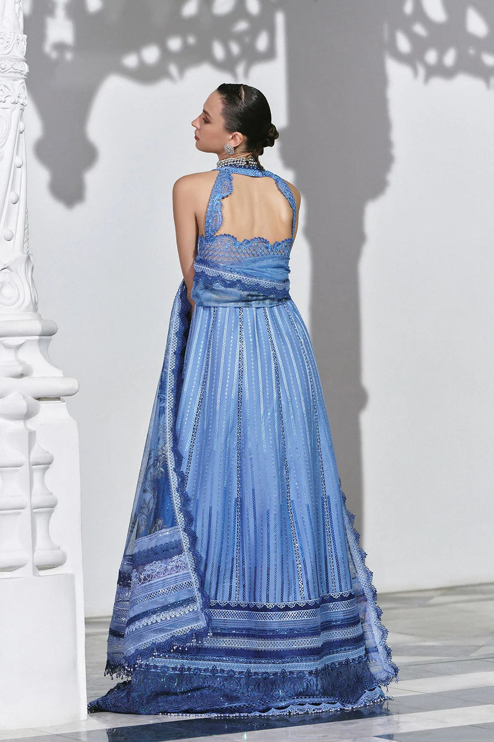 Woman wearing a blue embroidered dress against a white wall