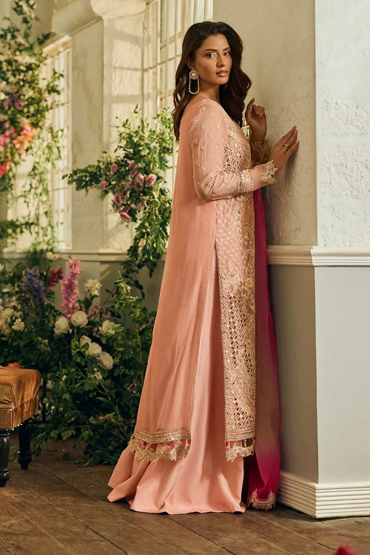 Woman in a peach traditional outfit with floral decorations in the background