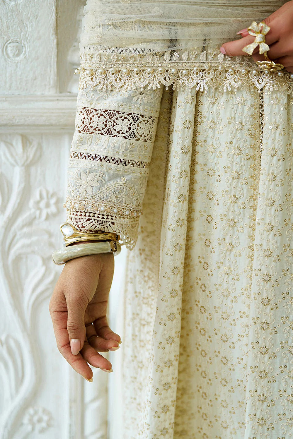 Close-up of a person wearing a white embroidered outfit with intricate patterns.