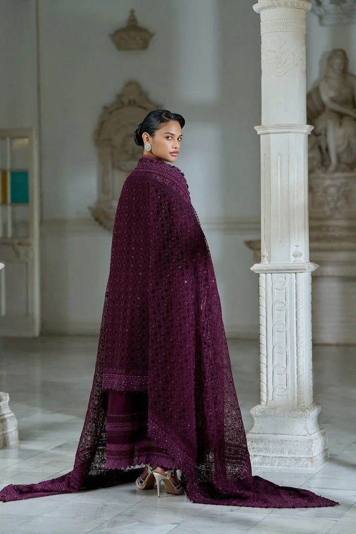 Woman wearing a long, dark purple garment in an elegant interior setting.