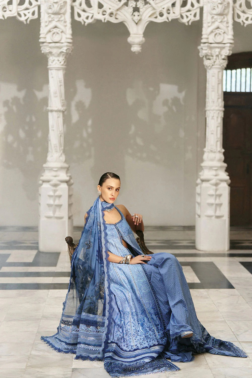 Woman in a blue traditional outfit sitting in an ornate hall