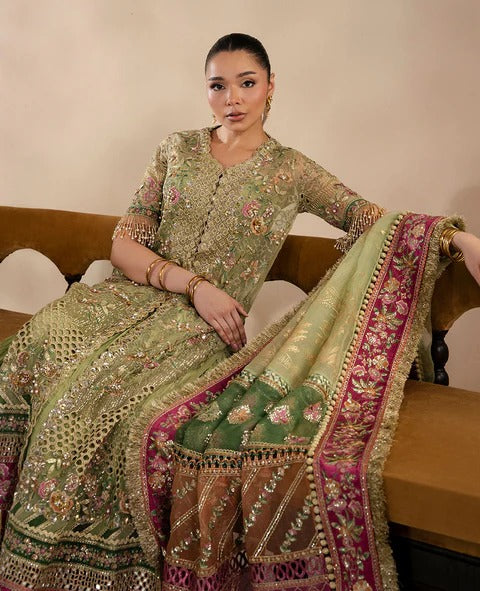 Woman in a traditional embroidered outfit sitting on a couch.