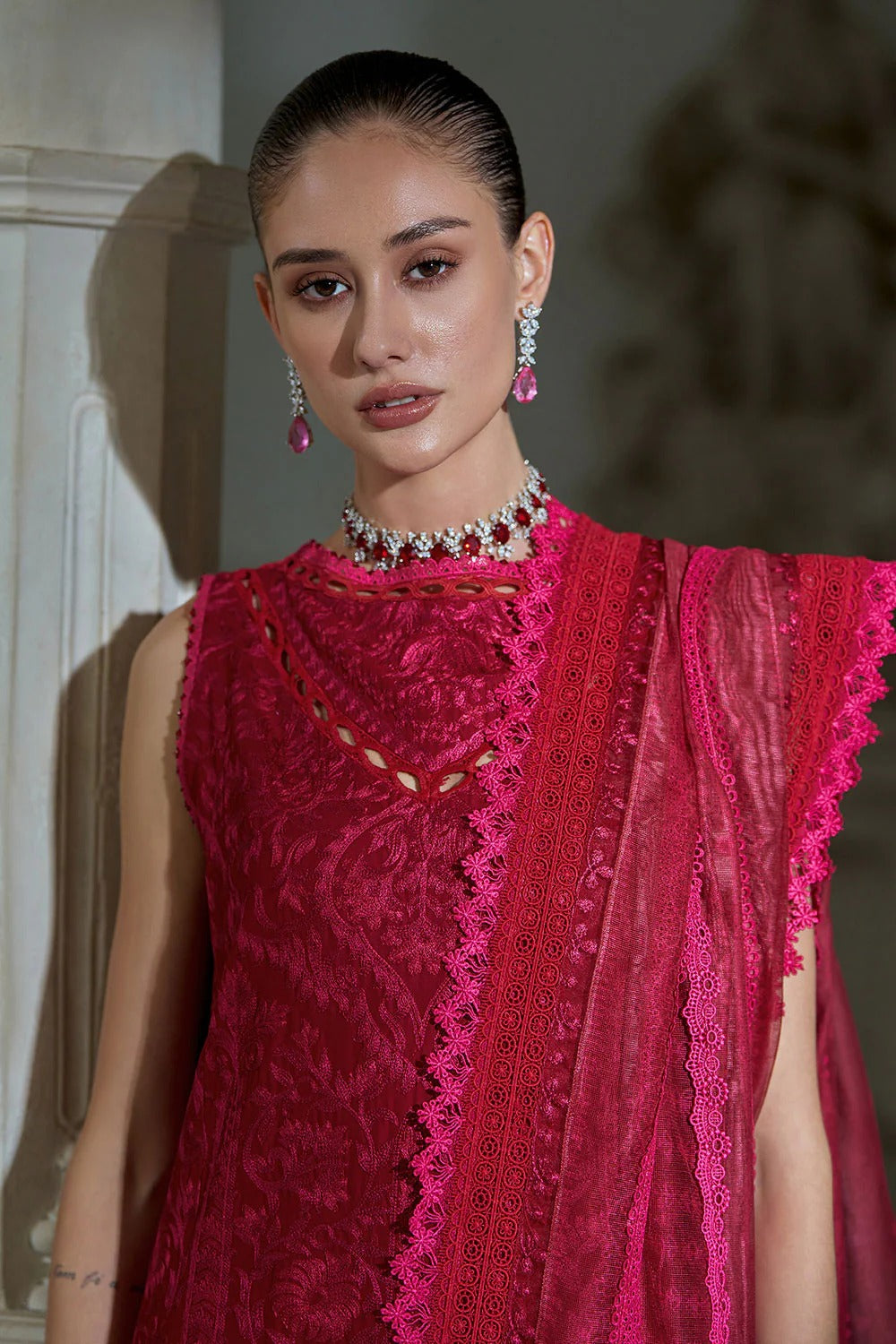 Woman wearing a bright pink saree with a matching blouse, standing against a neutral background.