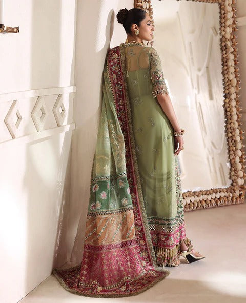 Woman in a green traditional outfit with a colorful dupatta standing in front of a mirror.