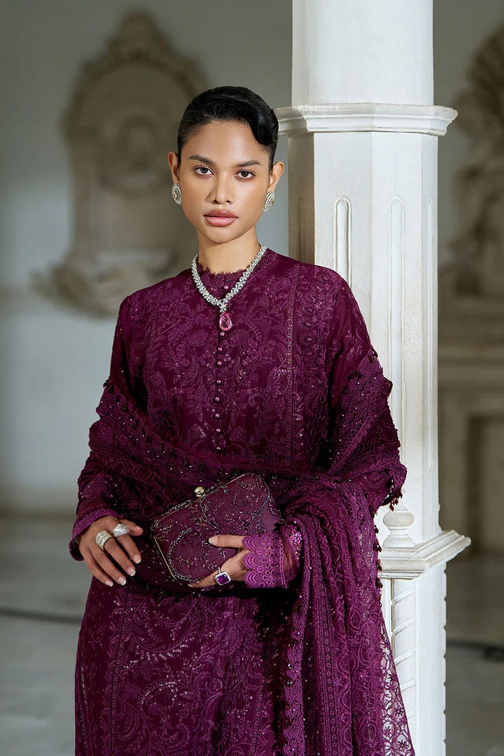 Woman in a purple traditional outfit standing indoors with decorative elements.