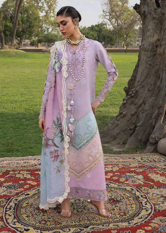 Woman in a traditional outfit standing on a colorful rug with trees in the background