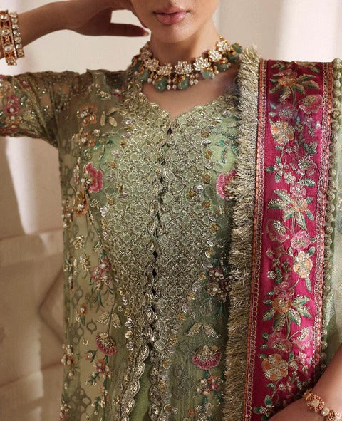 Close-up of a person wearing an intricately designed green and pink traditional outfit with floral patterns.