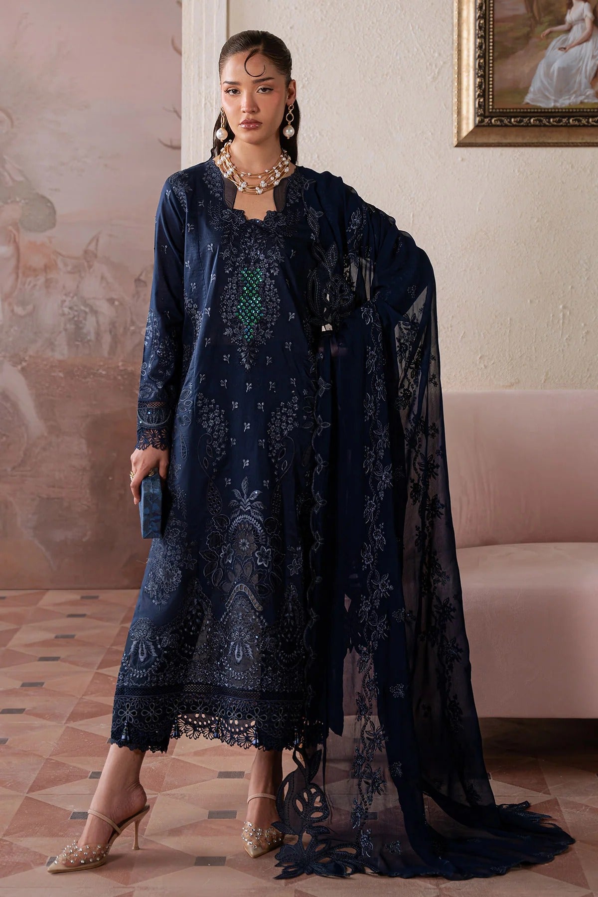 Woman in a dark blue embroidered dress with a matching shawl in an elegant room.
