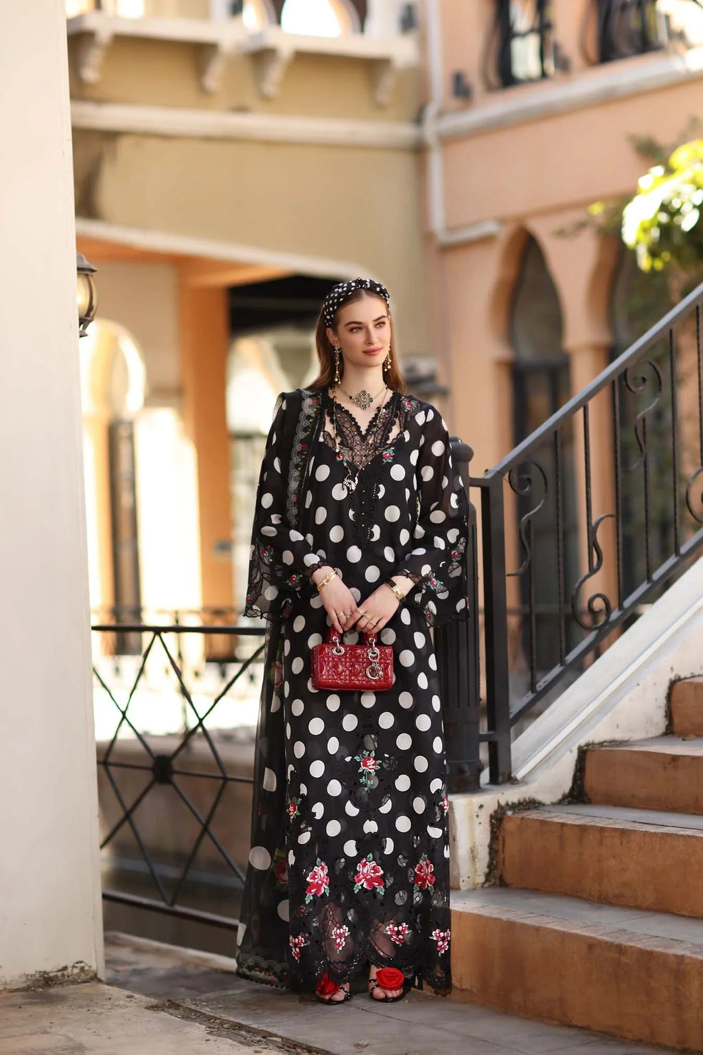 Woman in a black floral dress standing on steps with a building in the background