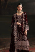 Woman wearing an intricately designed maroon and gold traditional outfit with a dark background
