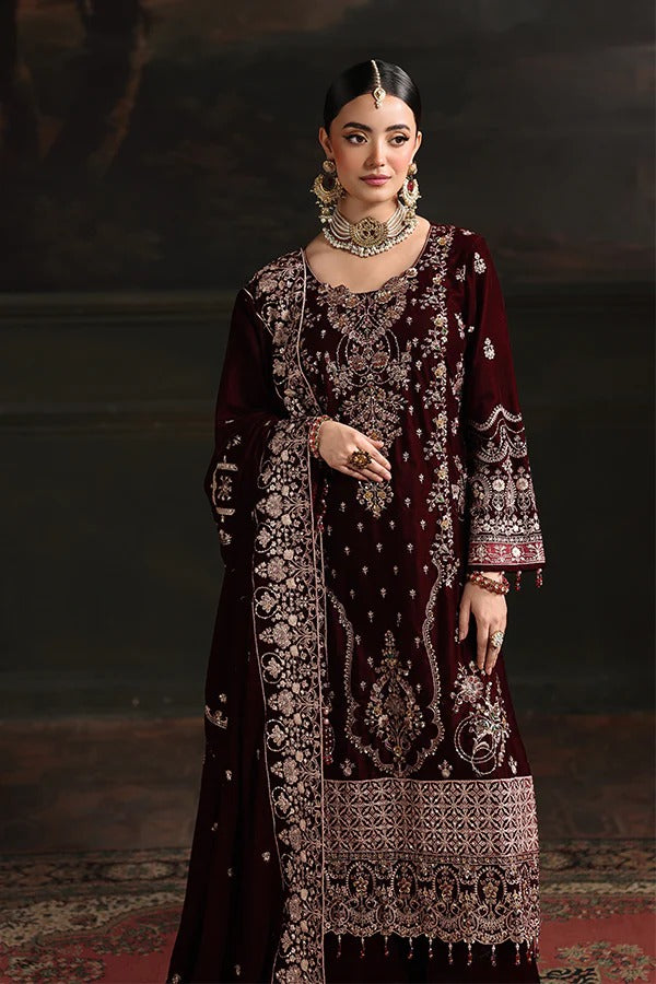 Woman wearing an intricately designed maroon and gold traditional outfit with a dark background