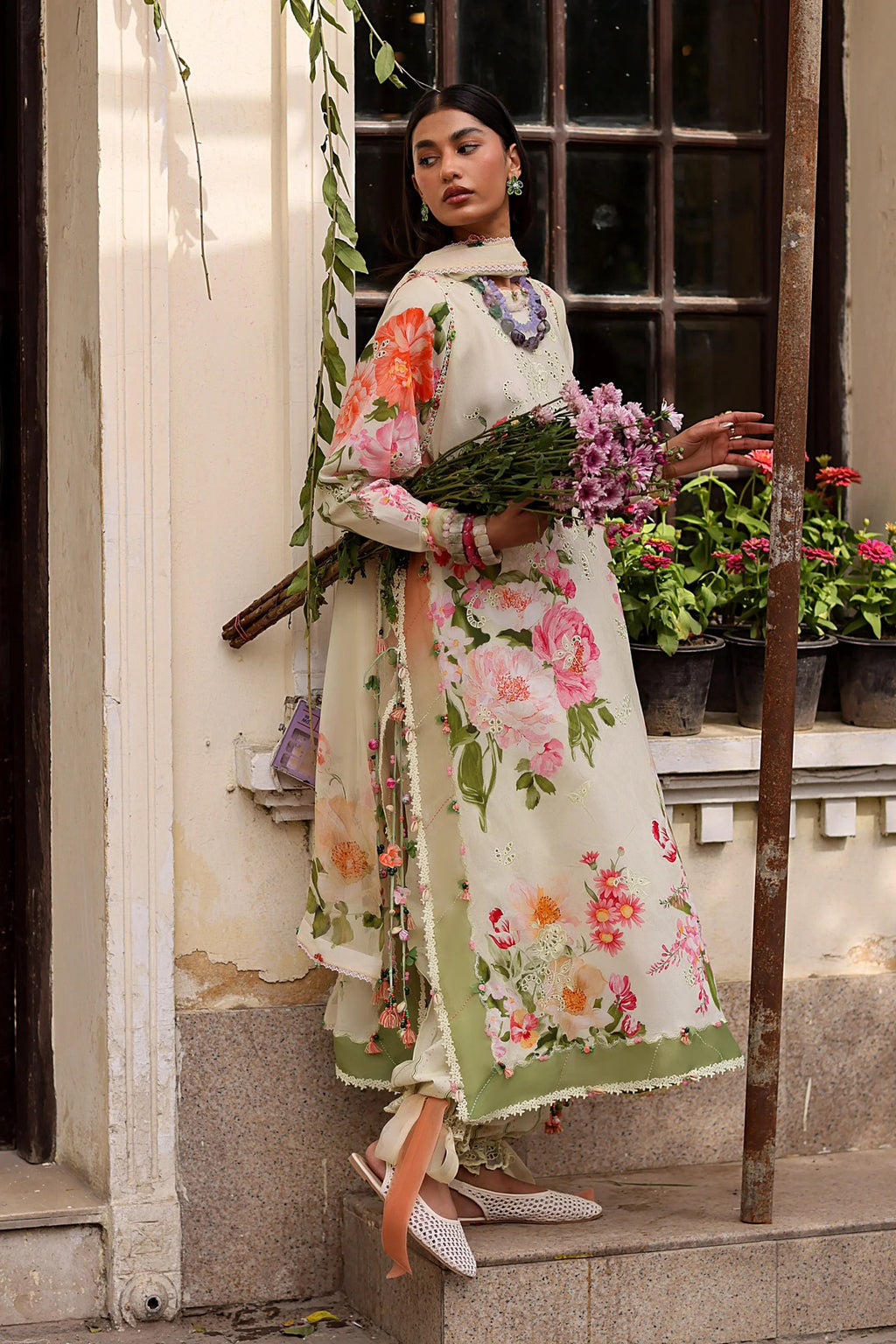 Woman in a floral dress standing on steps with plants in the background