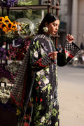 Woman in a floral dress holding a patterned handbag near a flower stand.