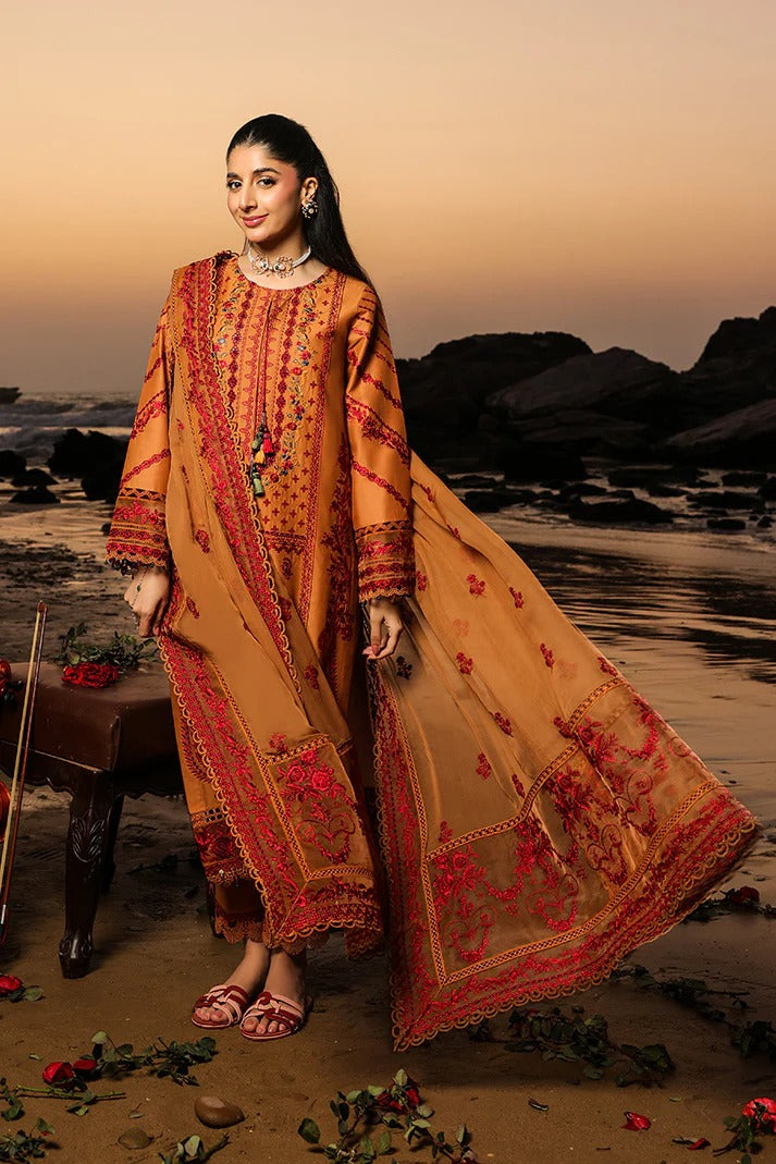 Woman in a traditional embroidered outfit standing on a beach at sunset.