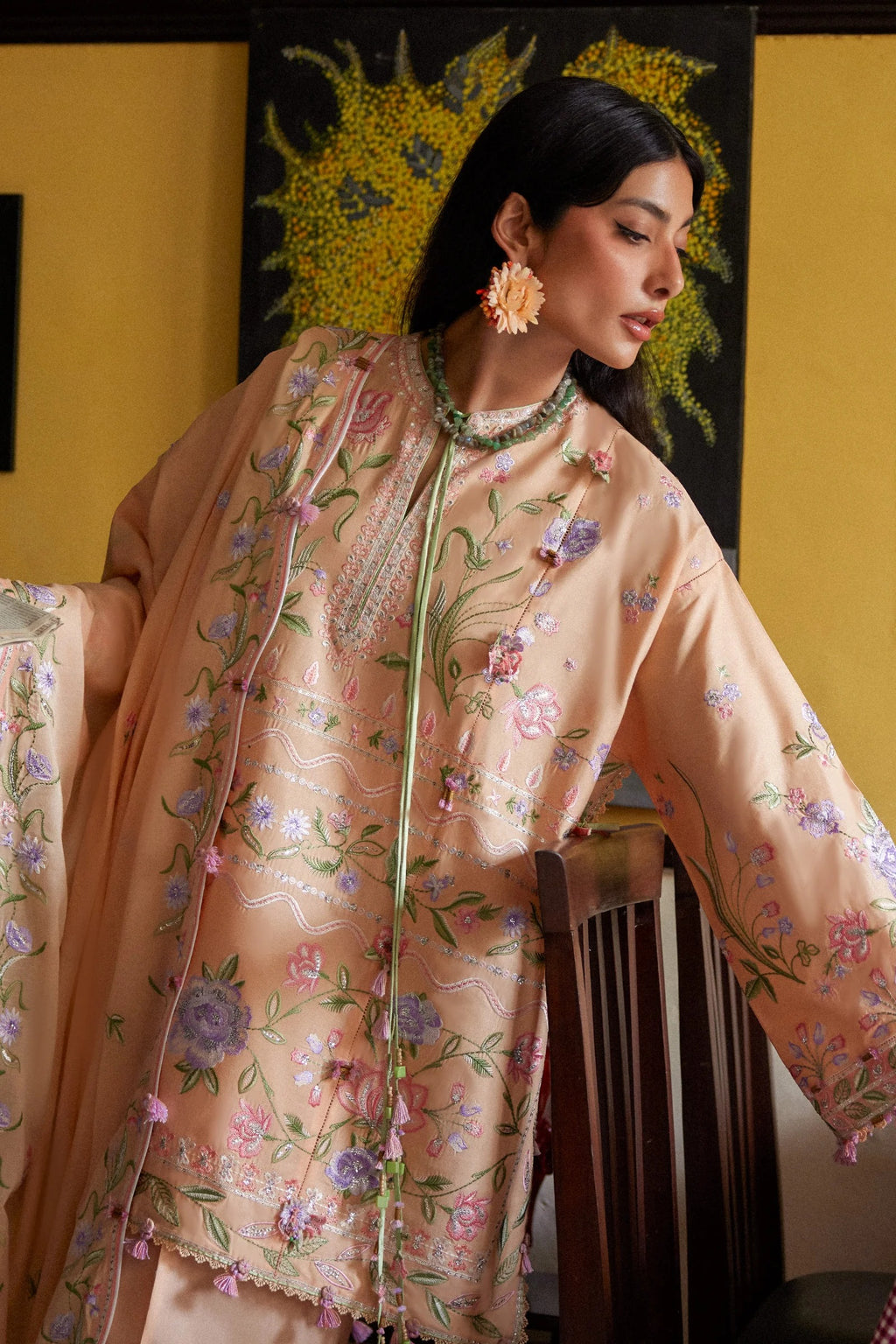 Woman wearing a floral embroidered outfit with a yellow background