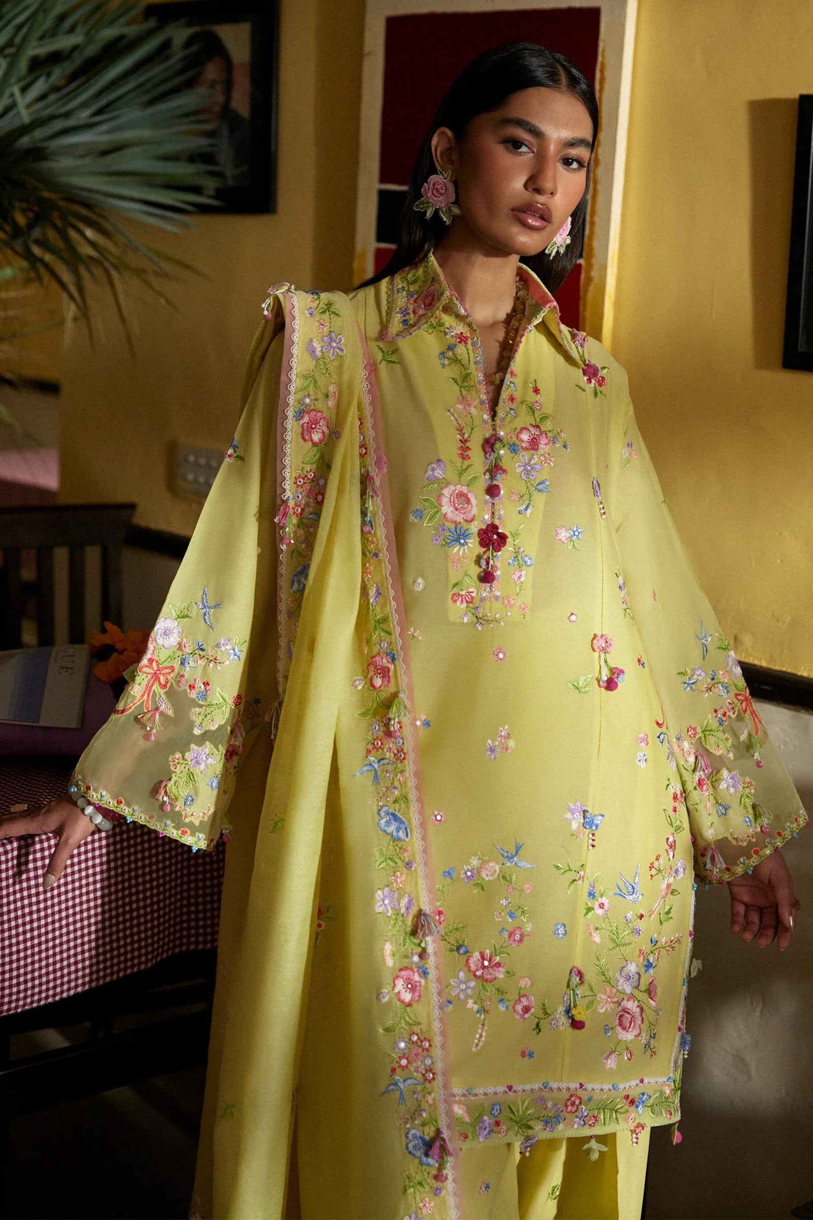 Woman wearing a yellow embroidered traditional outfit indoors.