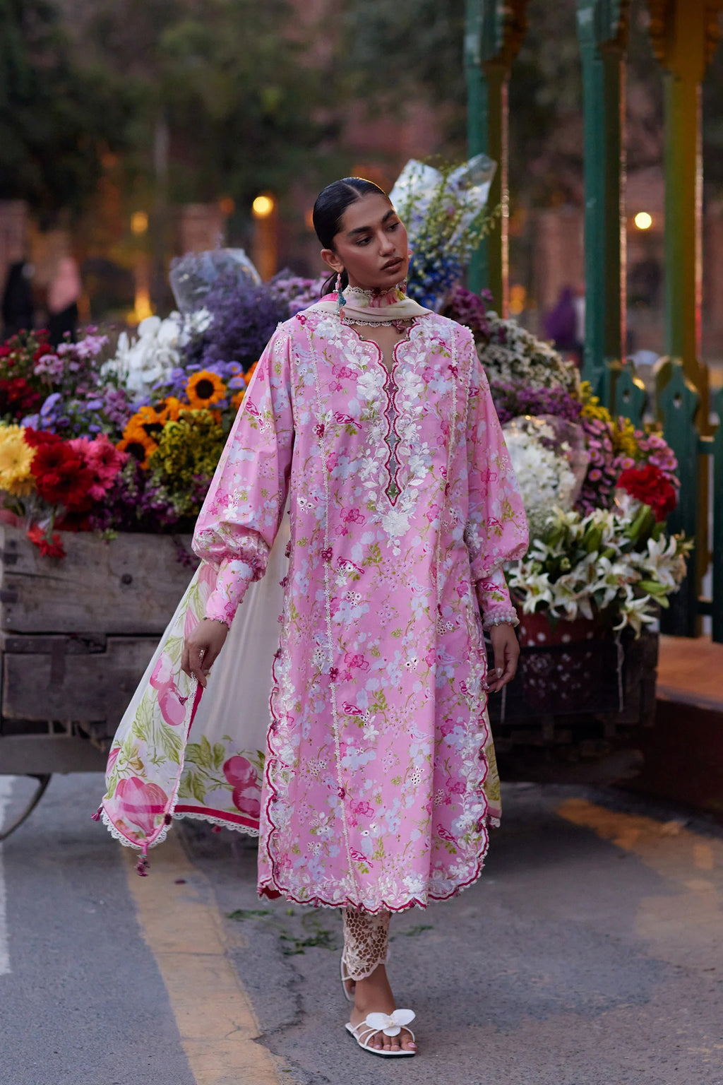 Woman in a pink floral dress standing in front of a floral display.