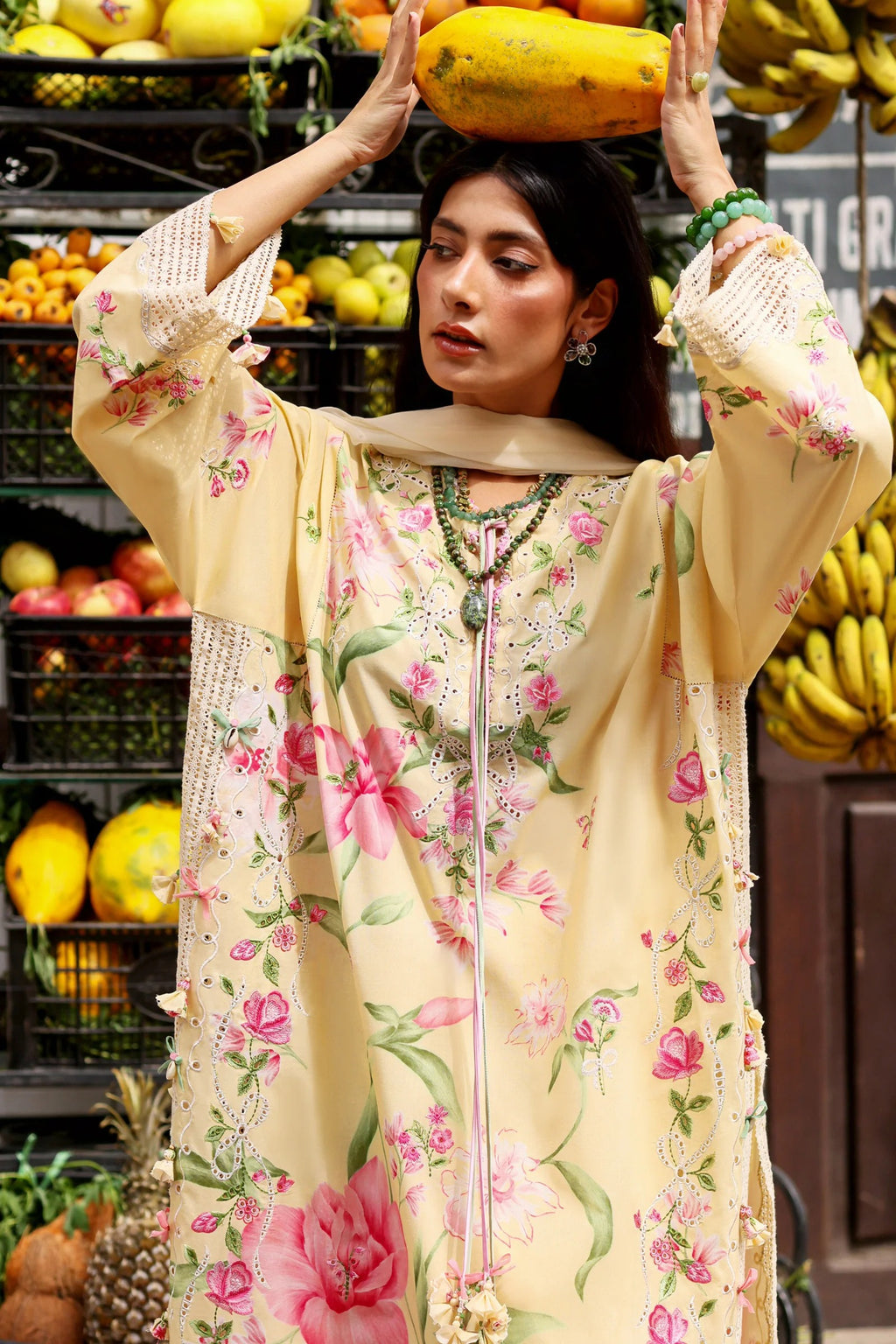 Woman holding a papaya in a market setting with fruits and vegetables in the background