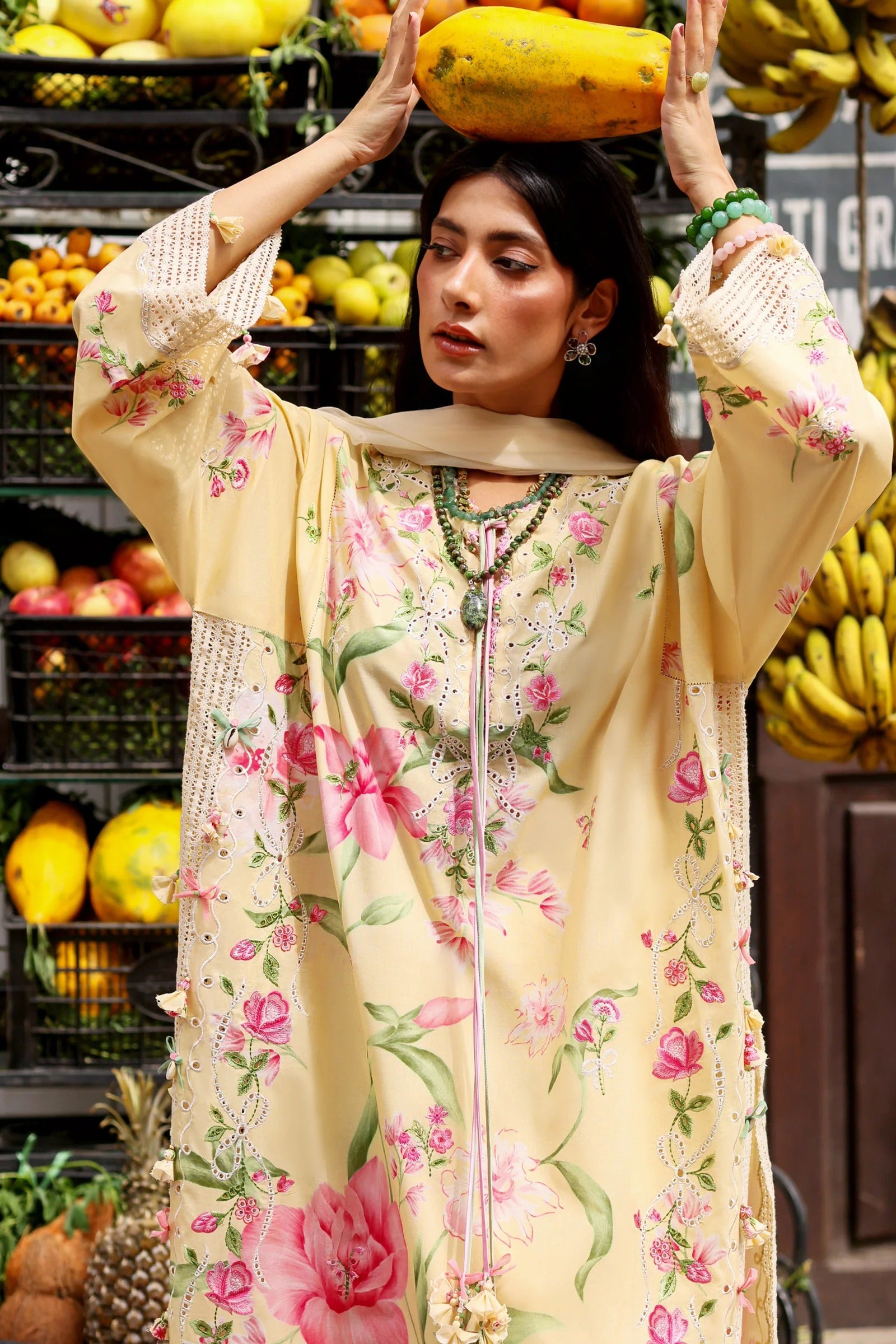 Woman holding a papaya in a market setting with fruits and vegetables in the background