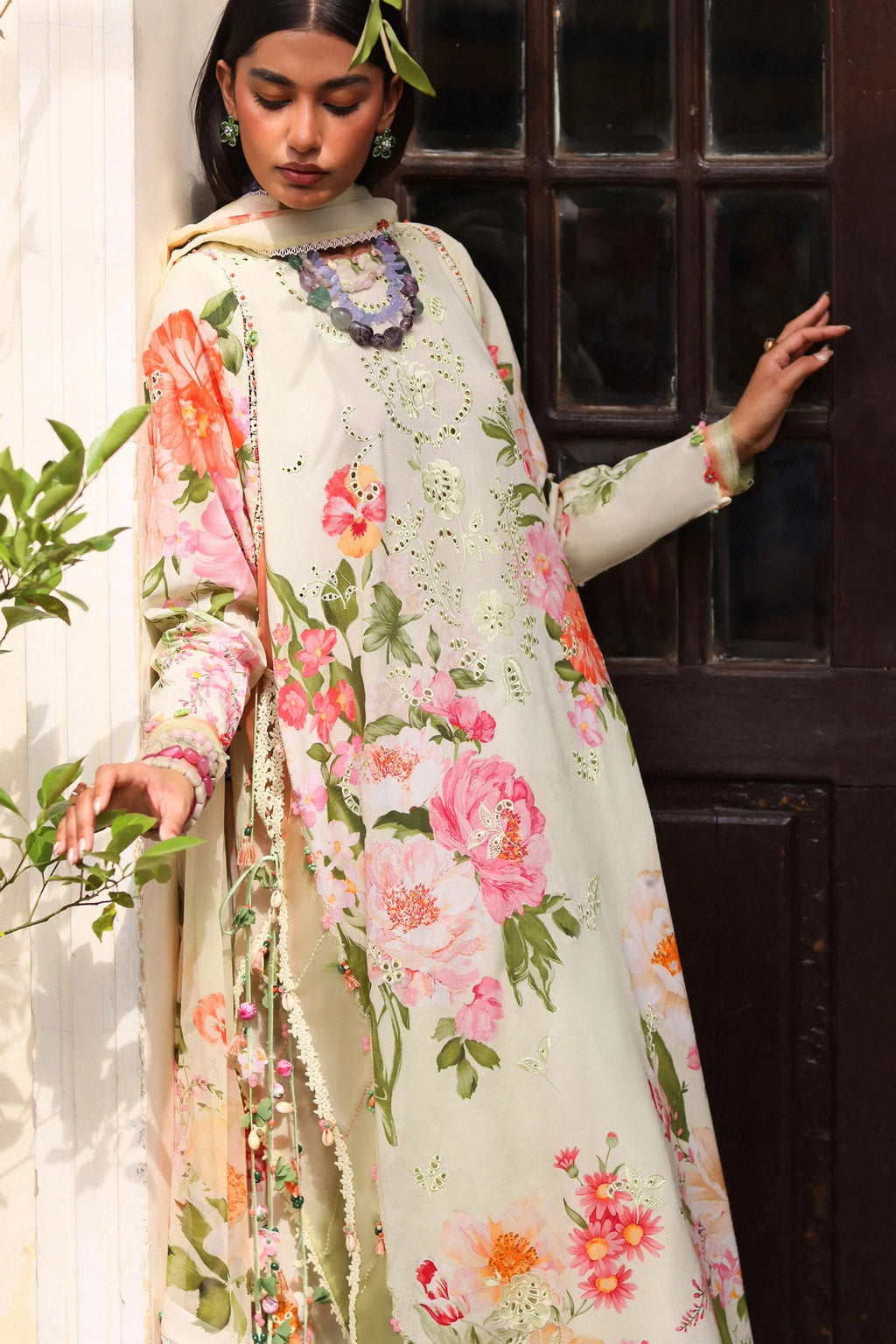 Woman wearing a floral dress standing next to a dark wooden door.