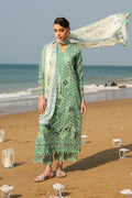 Woman in a green traditional outfit with a scarf on a beach