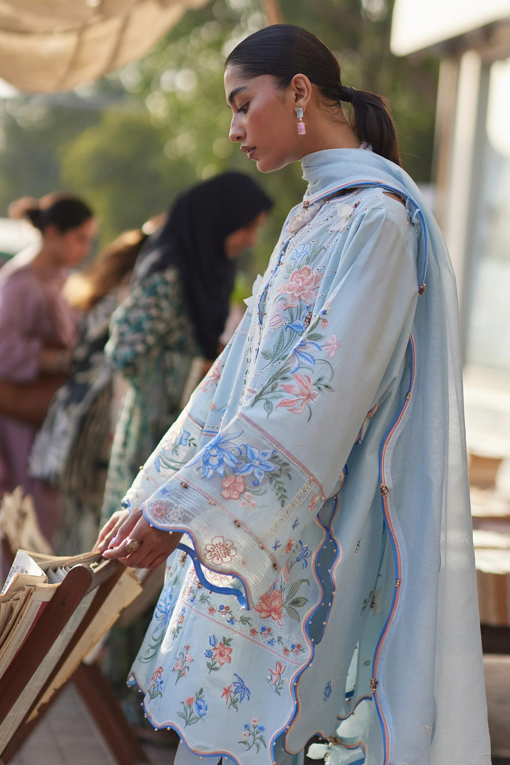 Woman wearing a light blue embroidered traditional outfit with blurred background