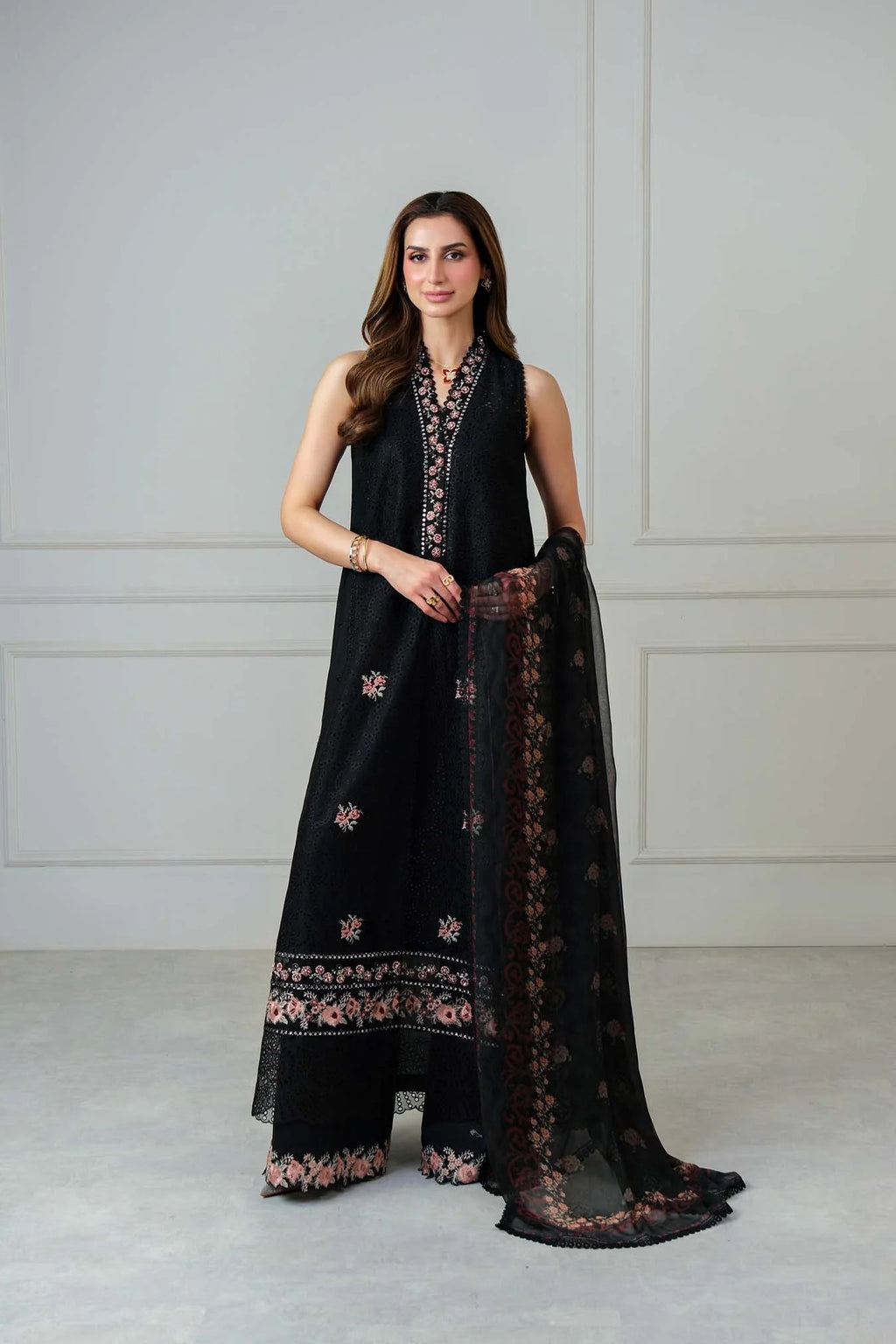 Woman wearing a black traditional outfit with floral patterns against a white background