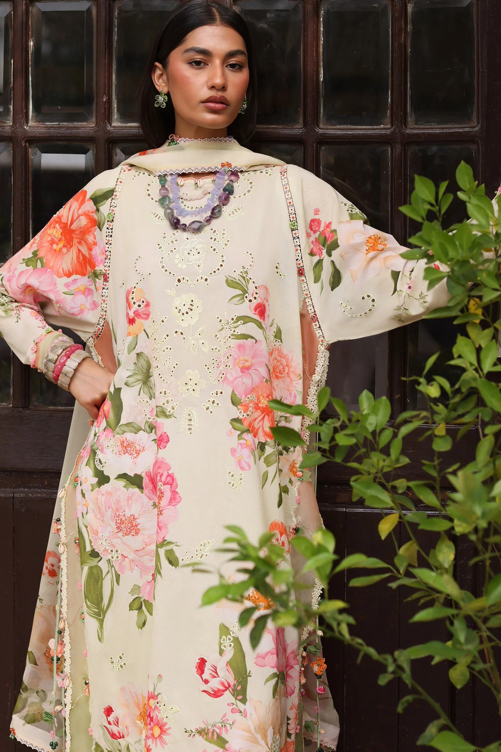 Woman wearing a floral dress with a dark background and greenery
