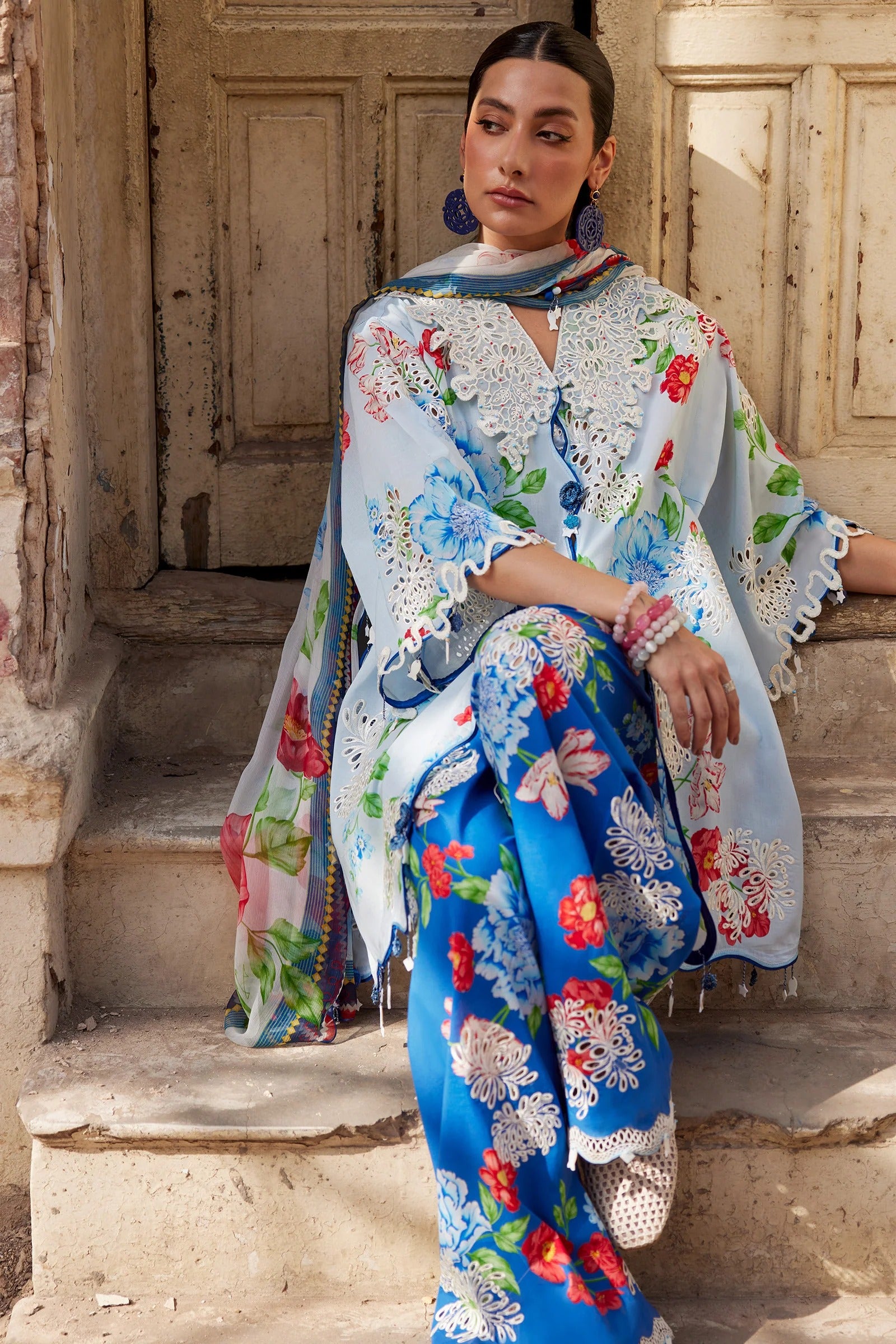 Woman wearing a floral outfit sitting on steps outdoors.