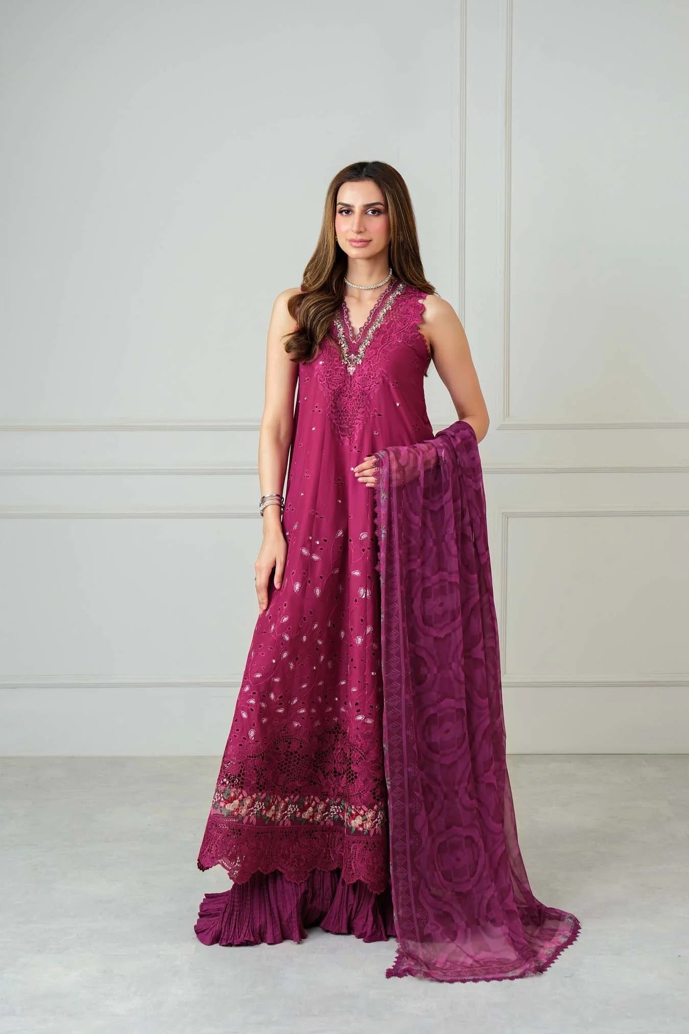 Woman wearing a magenta traditional outfit with a matching dupatta against a white background