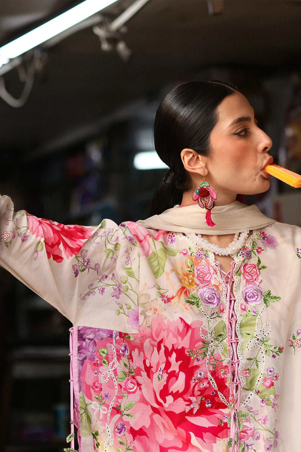 Woman in a floral outfit eating a carrot with a blurred background