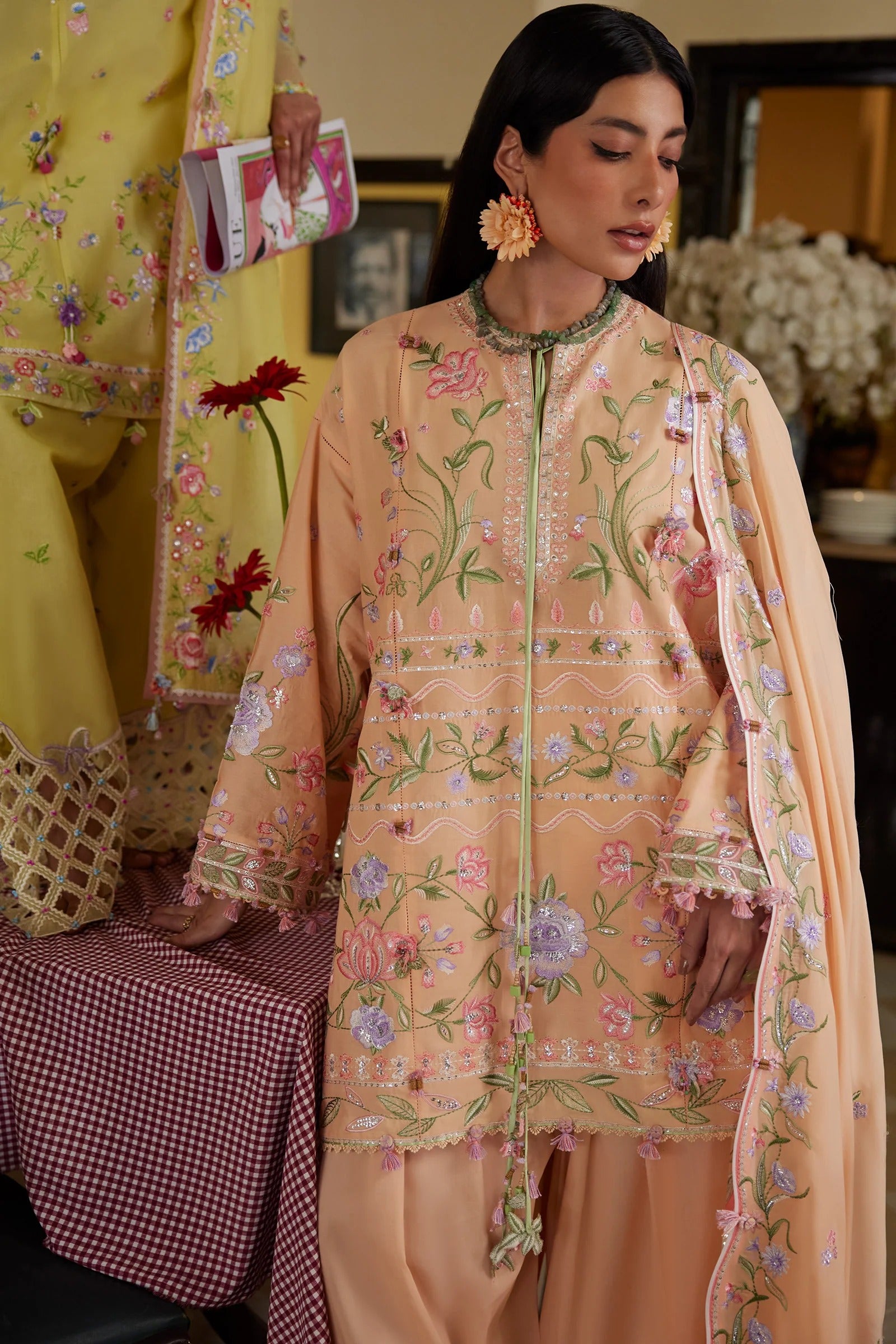 Woman wearing a peach embroidered outfit with a matching dupatta, standing indoors.