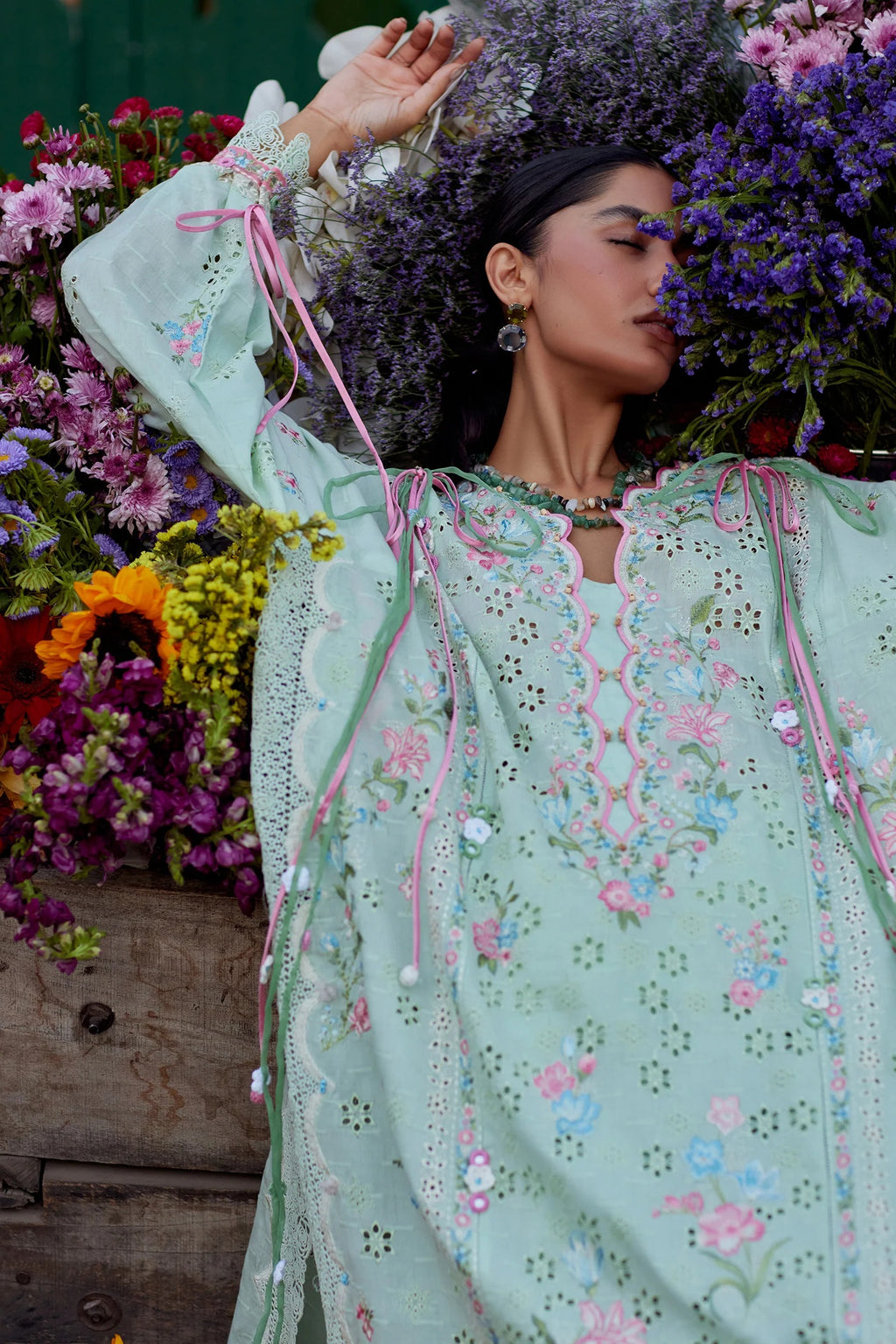 Woman in a light green embroidered dress with flowers and a wooden cart in the background