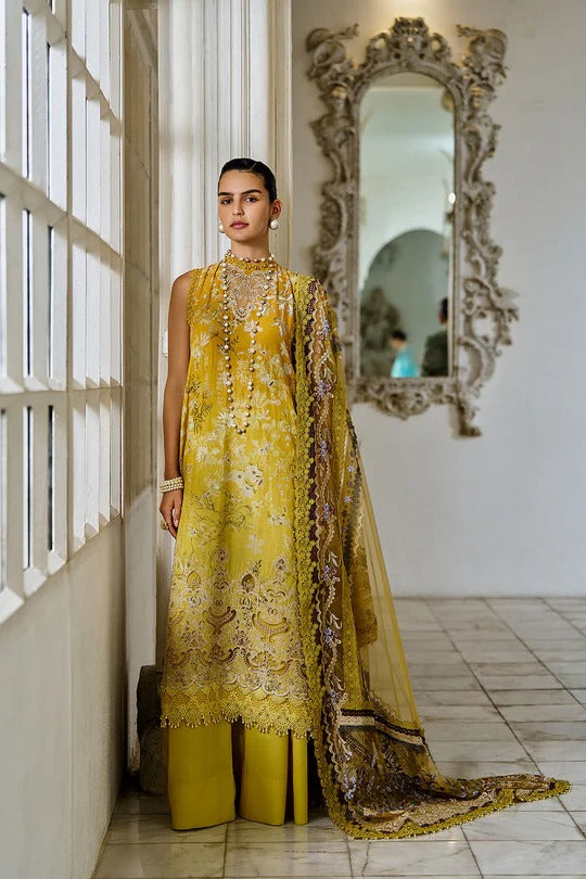 Woman in a yellow embroidered outfit standing in a room with a decorative mirror.
