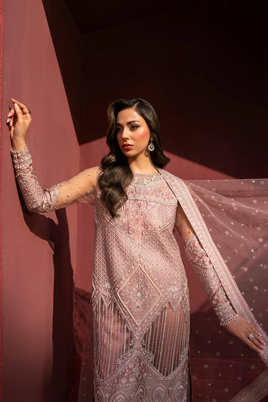 Woman in a glamorous dress with intricate detailing against a dark background