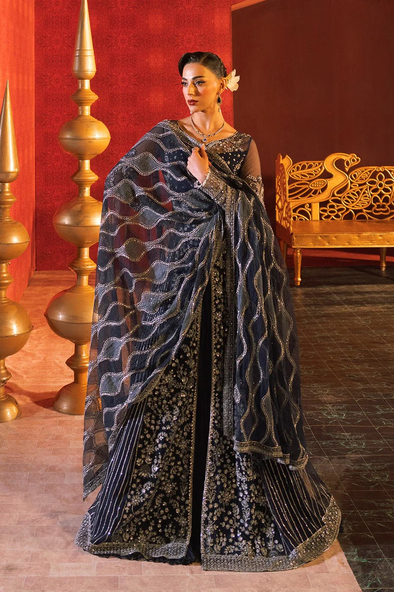 Woman in a black saree with gold patterns in a decorated room.