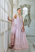 Woman in a light pink traditional outfit standing in a room with large windows and decorative mirror.