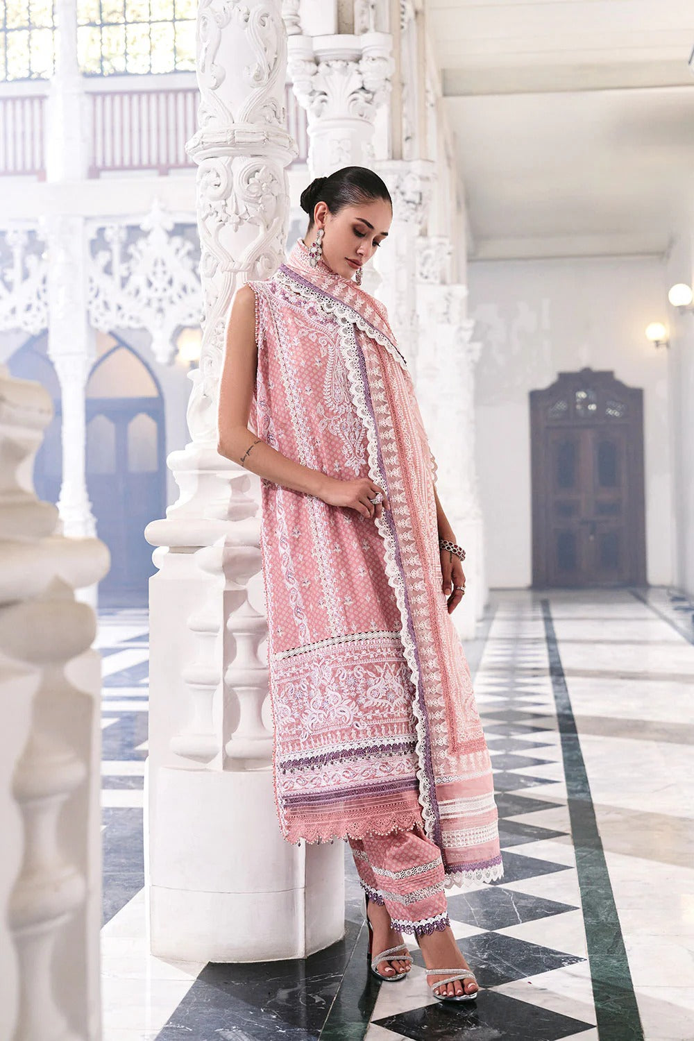 Woman in a pink traditional outfit with a matching dupatta in an ornate hall.