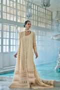 Woman in a traditional beige embroidered outfit standing by a pool with large windows in the background