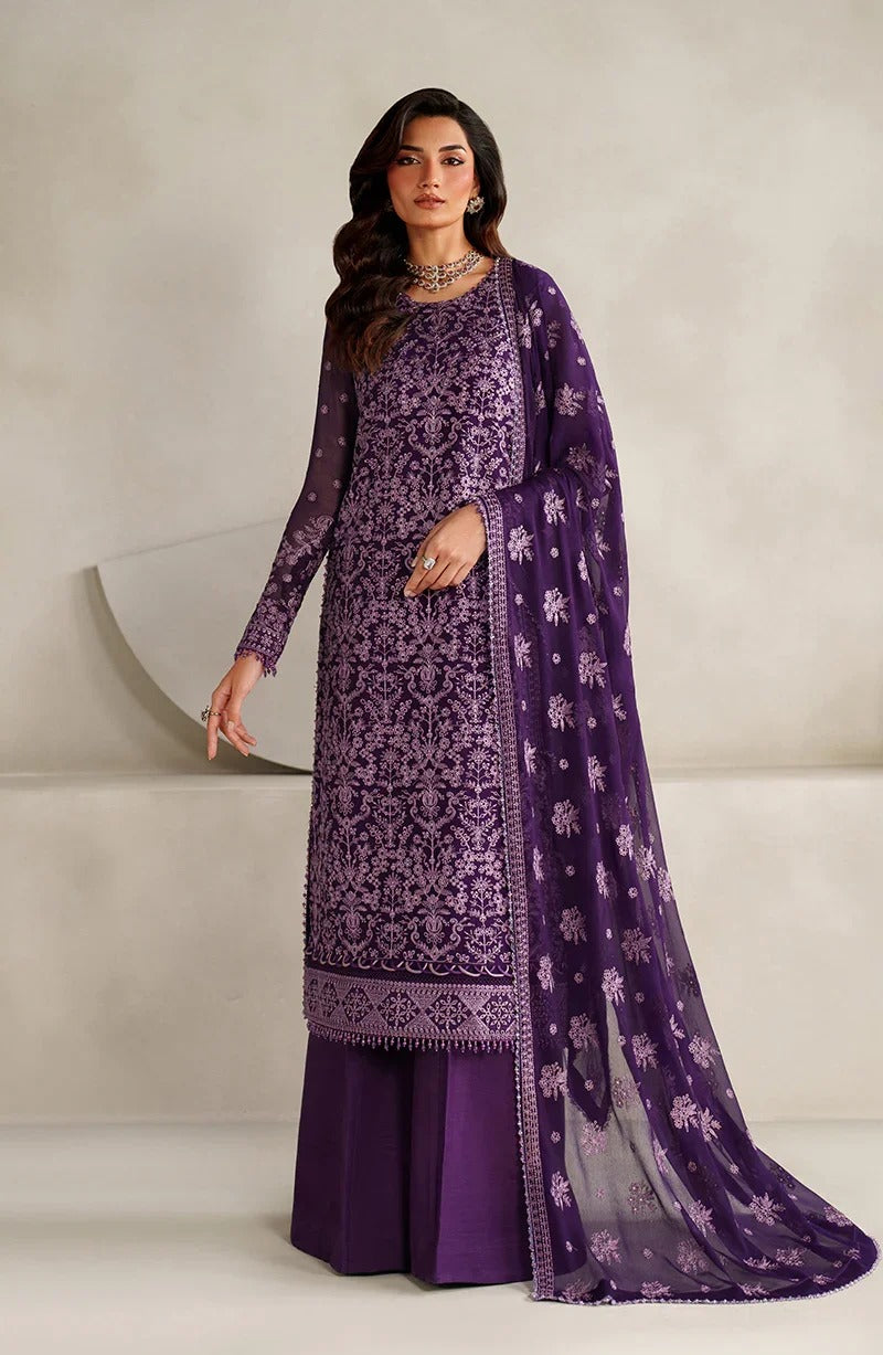 Woman wearing a purple embroidered traditional outfit with a matching dupatta on a neutral background