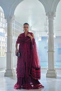 Woman in a vibrant pink traditional outfit standing in an elegant white architectural setting.
