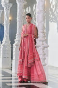 Woman in a pink traditional outfit standing against white marble columns.