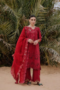 Woman in a red embroidered outfit standing in front of palm trees