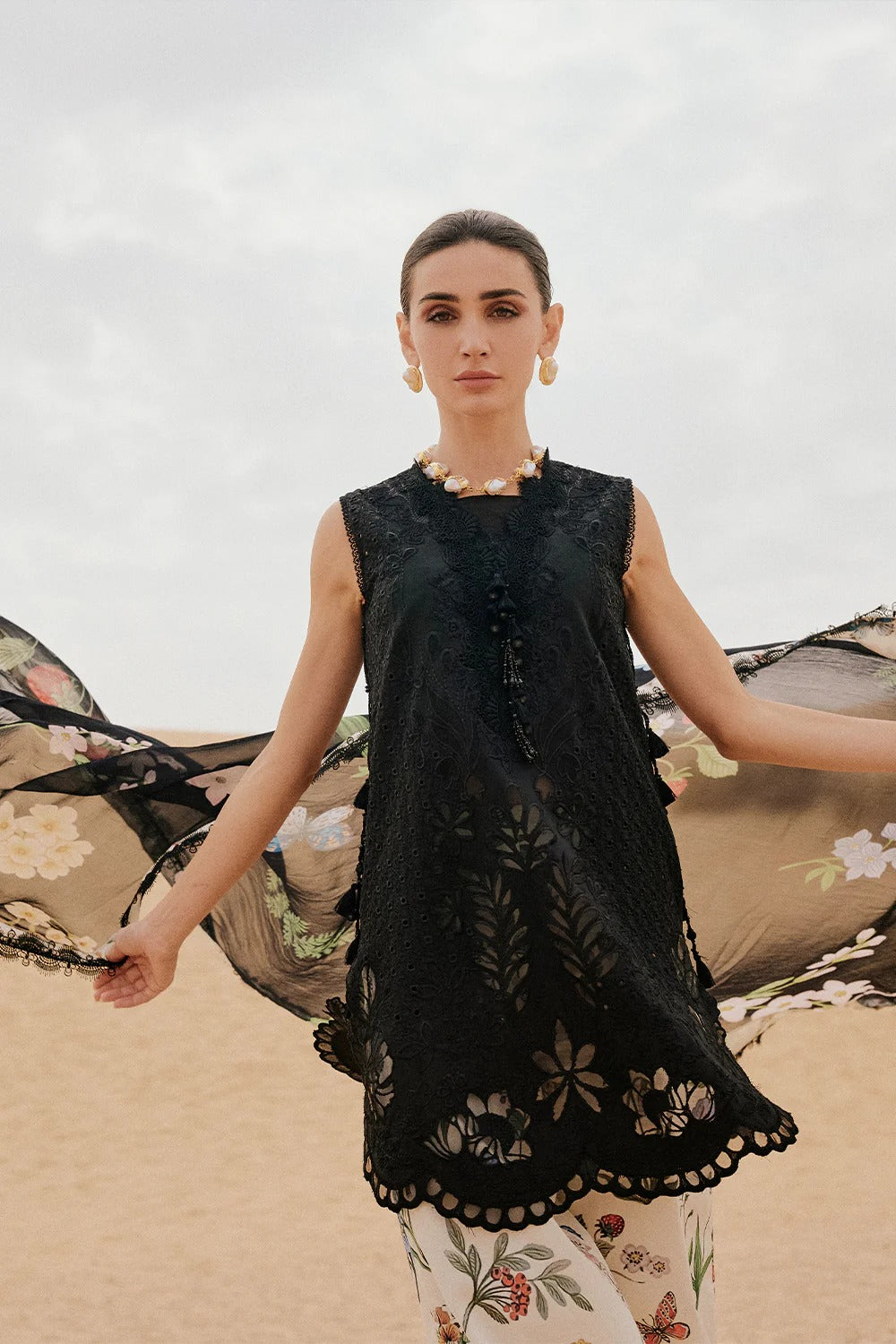 Woman wearing a black embroidered dress with floral patterns in the background
