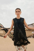 Woman wearing a black embroidered dress with floral patterns in the background