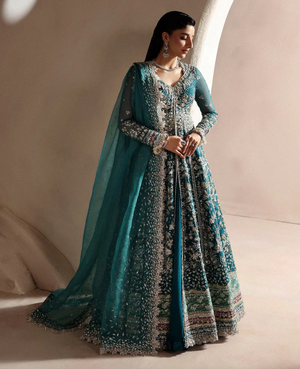 Woman wearing a traditional outfit with a blue dupatta against a neutral background